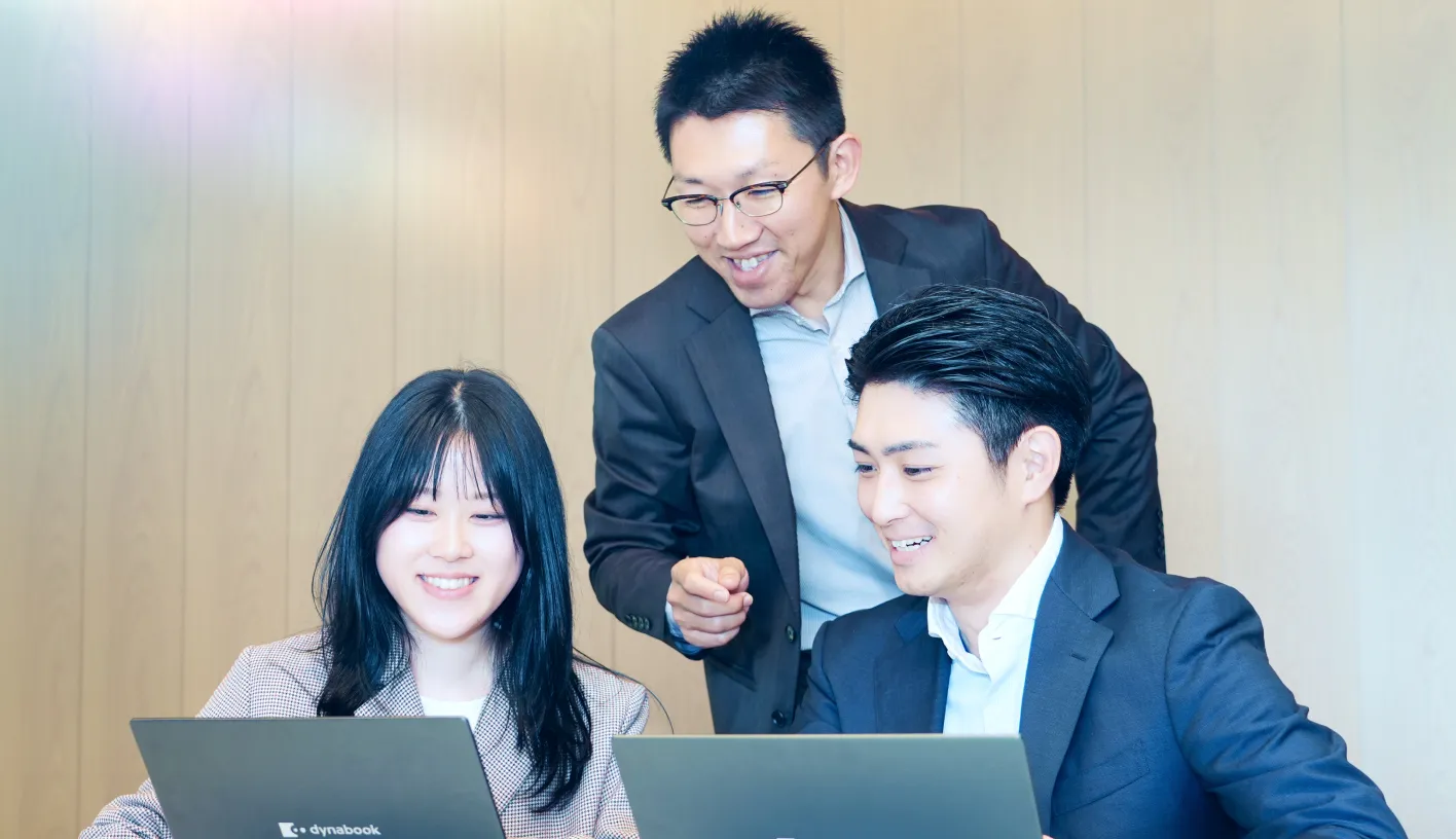 ノートPCの画面を見ながら話す3名の社員