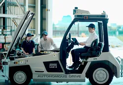 自動運転フォークリフトの前で打ち合わせをする社員3名