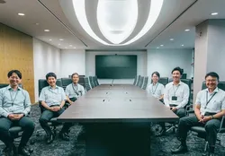 会議室の大テーブルを囲んで並ぶ社員たち
