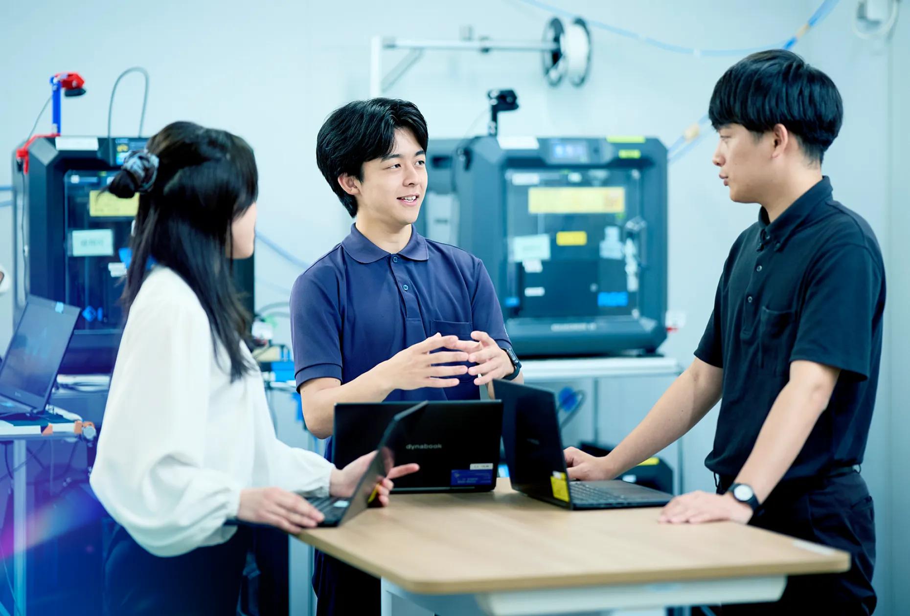 研究設備の前で打ち合わせをする社員3名