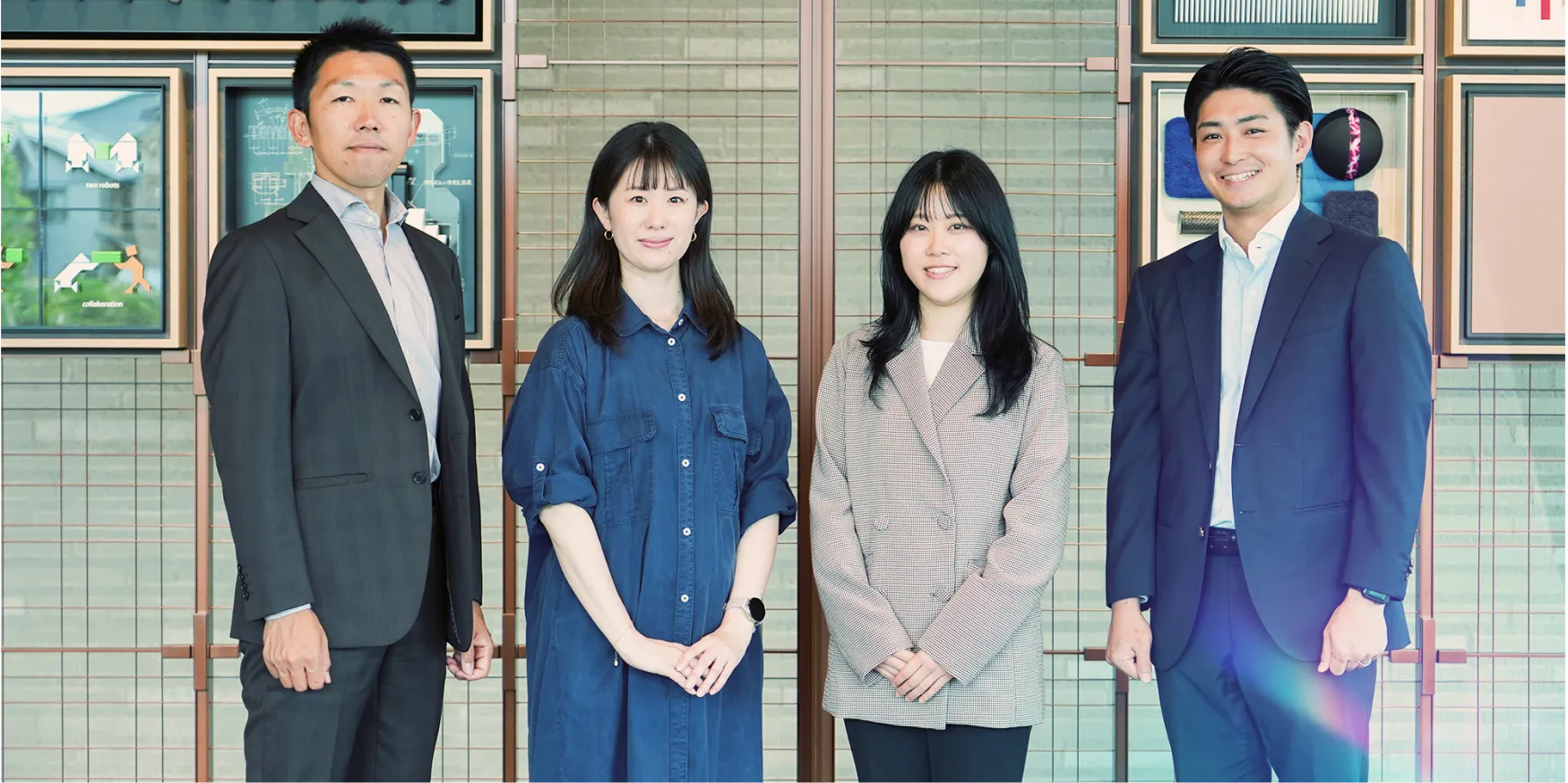 社内のアート作品の前に並ぶ4名の社員